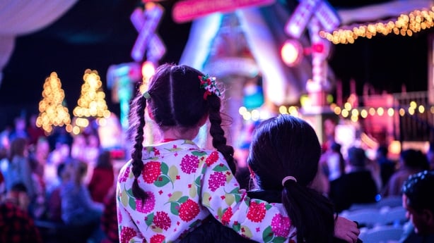 A Mother and child waiting to see Santa at a Christmas tree lighting ceremony.