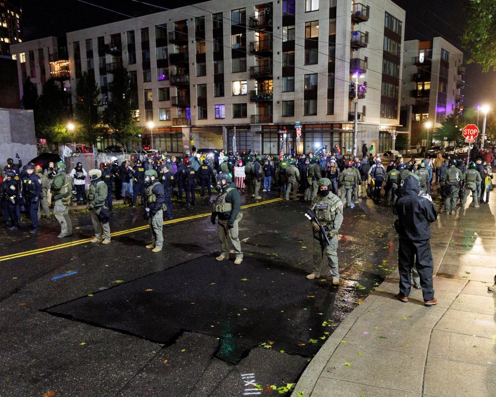 Dozens of national guard soldiers in formation on a rainy street at night.