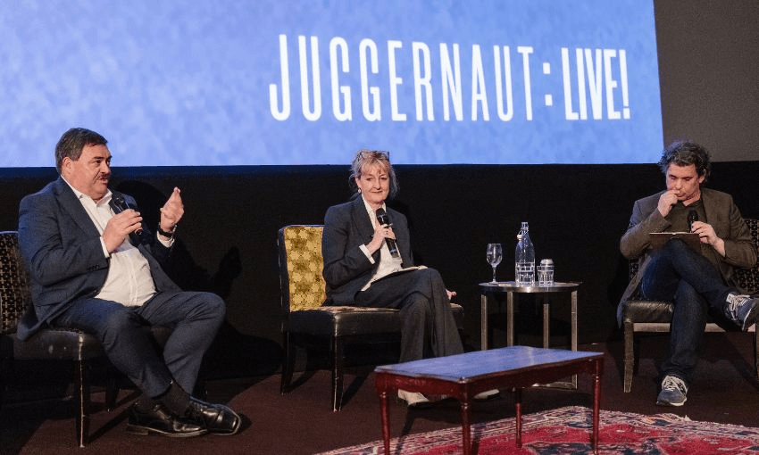 Chris Wikaira, Linda Clark and Toby Manhire sit together on The Embassy theatre stage, with the screen reading: "Juggernaut: Live!"