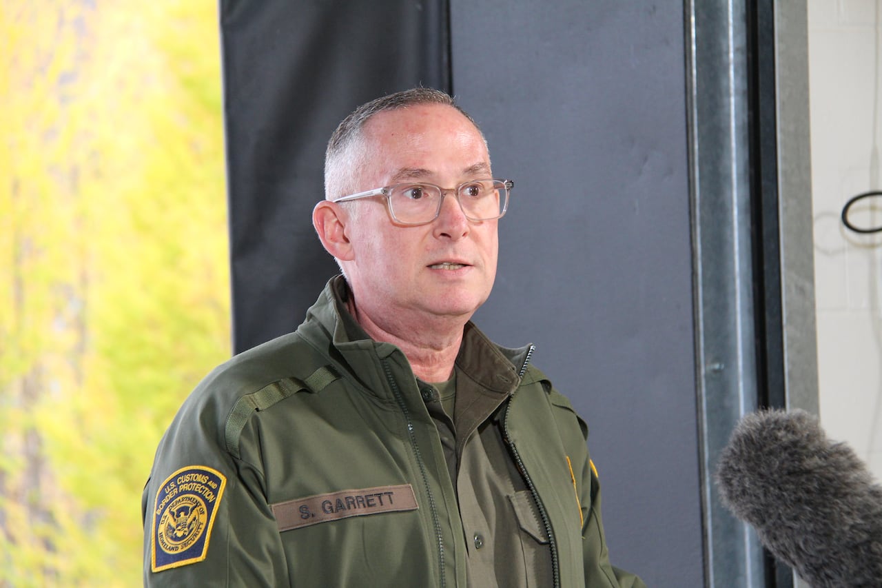A man on a green suit stands behind a podium.