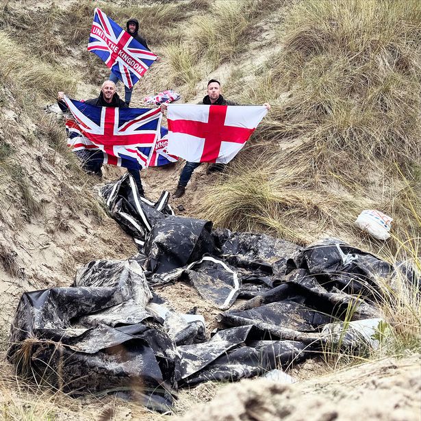 Bridge and Thomas proudly holding flags, standing next to the apparent remnants of a boat. 