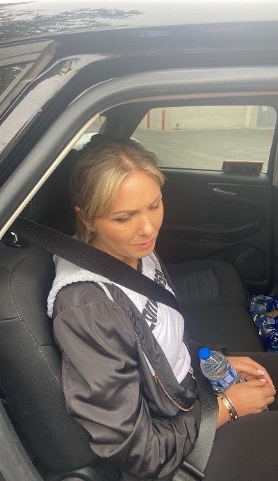 Victoria Sorocean, a woman wanted for murder, seated in the back of a vehicle with a seatbelt on and holding a water bottle.