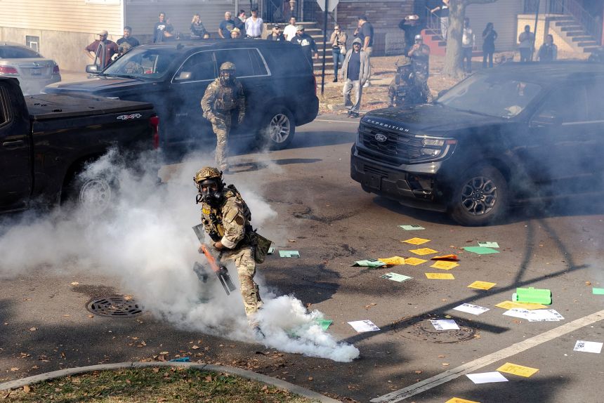 A federal agent prepares to throw a tear gas canister at community members during clashes in Chicago on October 14.