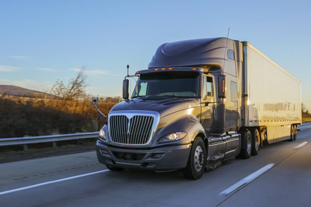 A big rig tractor trailer semi truck on a freeway.