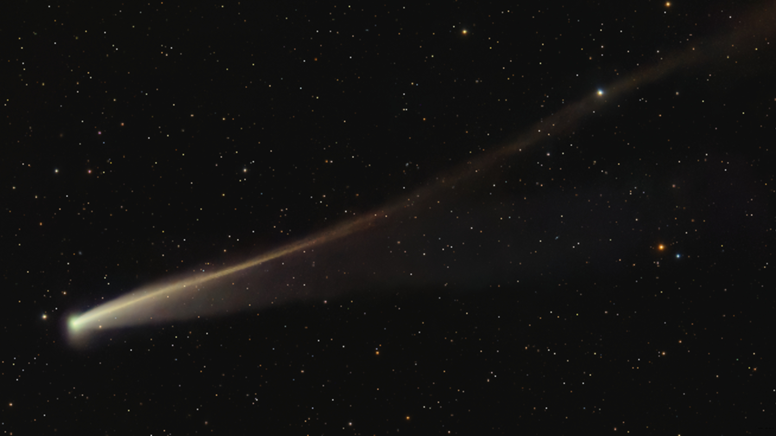 A photo of a gold-colored comet with a long rippling tail in the night sky