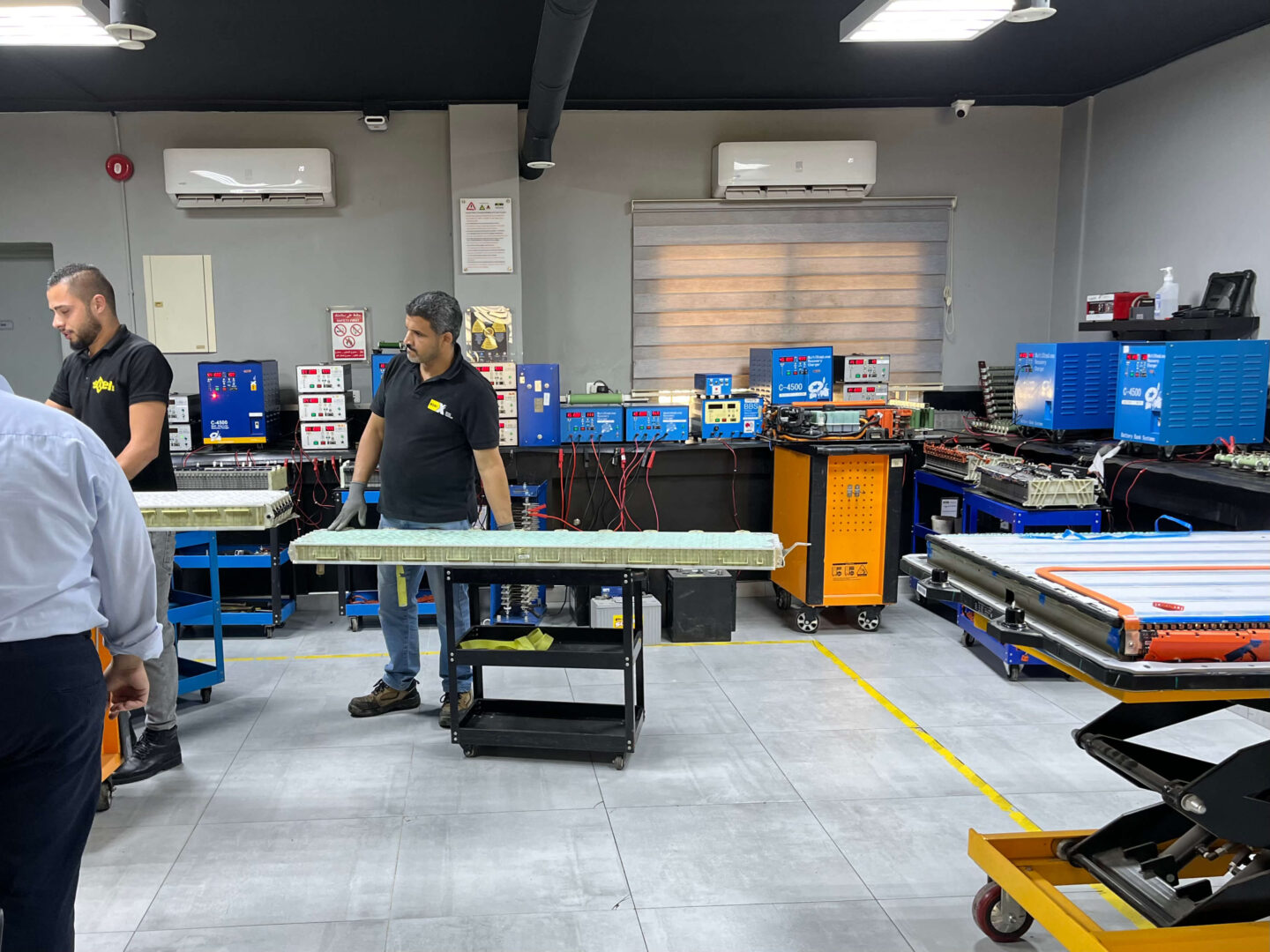 A man rolls a long battery on a trolley in a workshop