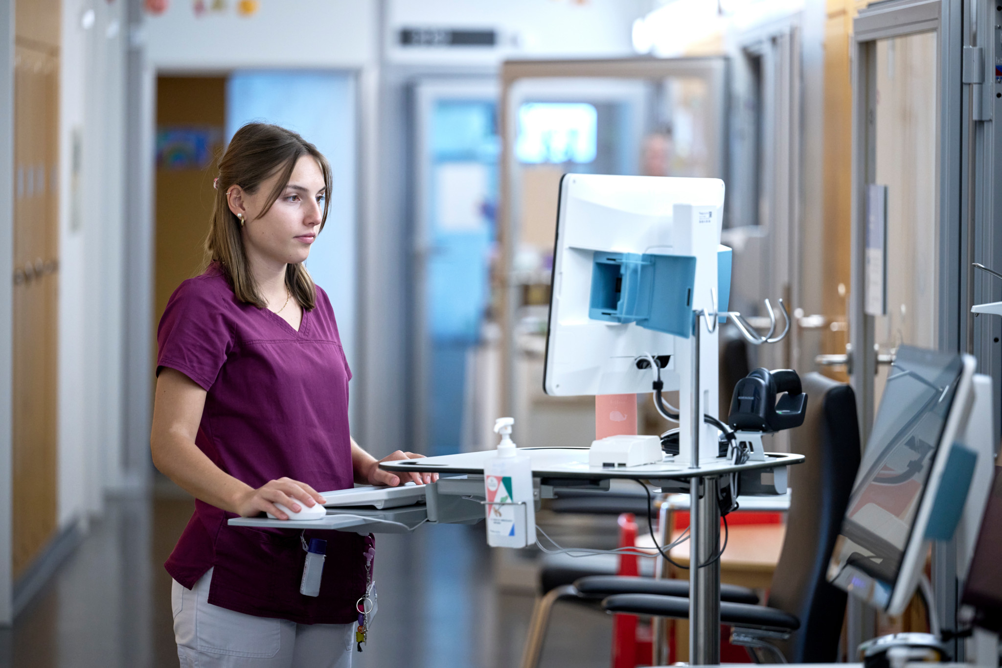 Krankenschwester in einer Kinderklinik bedient einen Computer zur Patientenverwaltung.