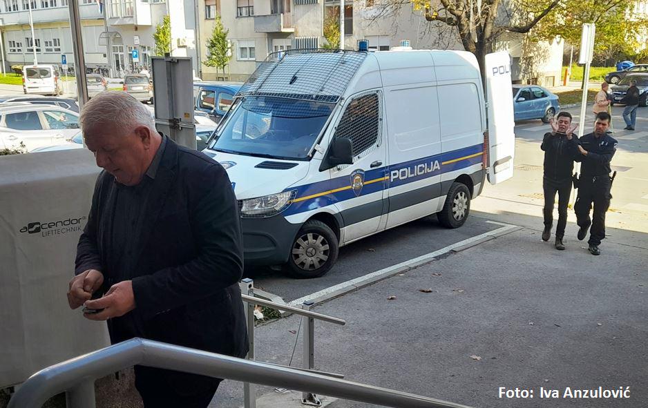 Josip Đakić ide prema sudu u Virovitici, dok iza njega novinar Ivan Žada pod policijskom pratnjom hoda vezan lisičinama - Đakić ga je tužio za klevetu (a u Zagrebu policajci priveli i strpali u maricu)