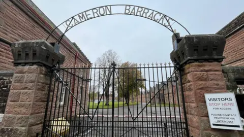 BBC The entrance to Cameron Barracks with a metal gate and a metal sign that says: "Cameron Barracks".