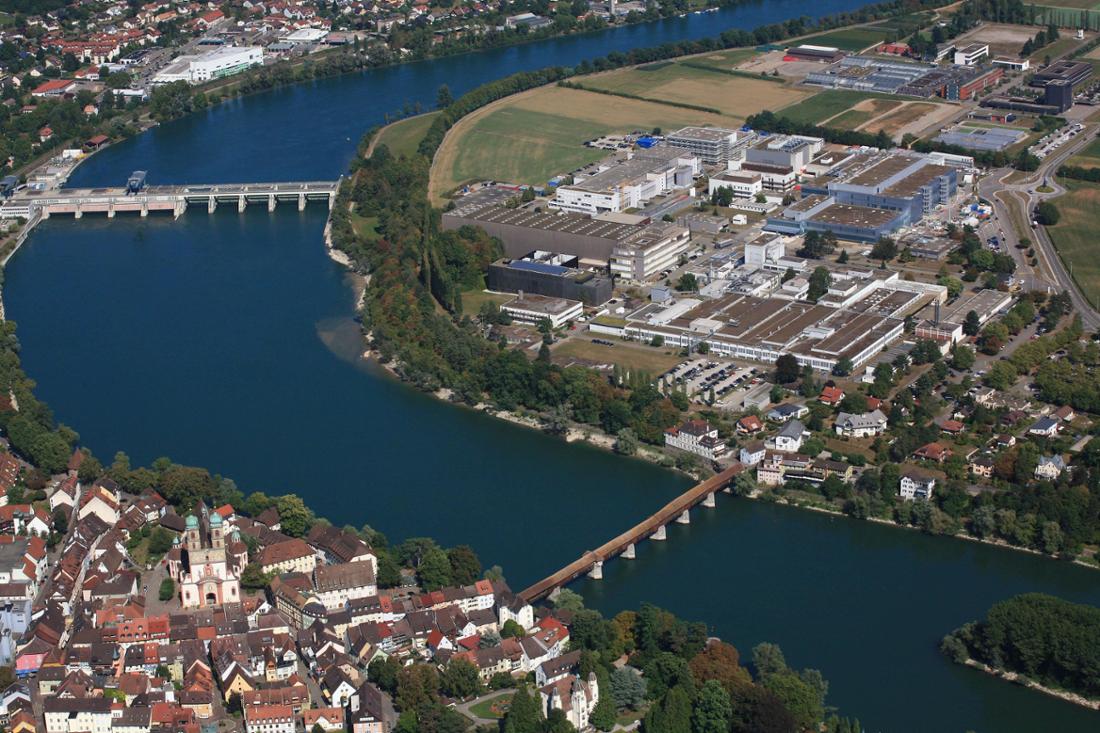 Blick auf Bad Säckingen (Baden-Württemberg, unten links), die Fridolinsbrücke und den Standort von Novartis in Stein (Kanton Aargau, Schweiz, Bildmitte). 