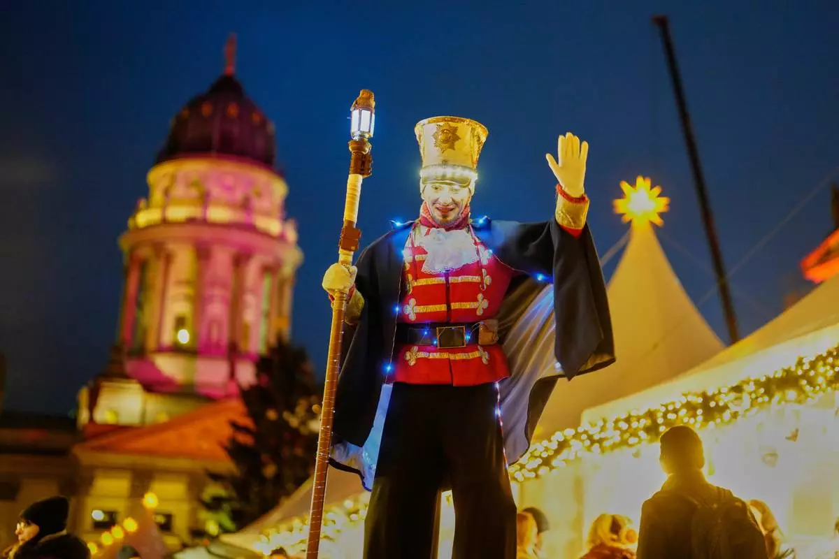 An artist on stilts performs on the illuminate Christmas Market at the Gendarmen Markt square in Berlin, Germany, Monday, Nov. 24, 2025. (AP Photo/Markus Schreiber)