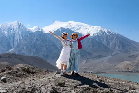 Getty Images Two women posing for a picture at White Sand Lake in Xinjiang's Akto County