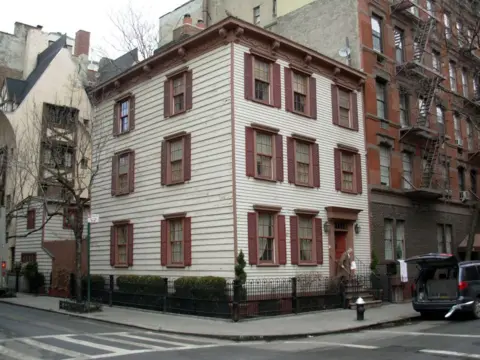 An apartment block in Greenwich Village, southern Manhattan, with a white exterior and brown windown shutters.