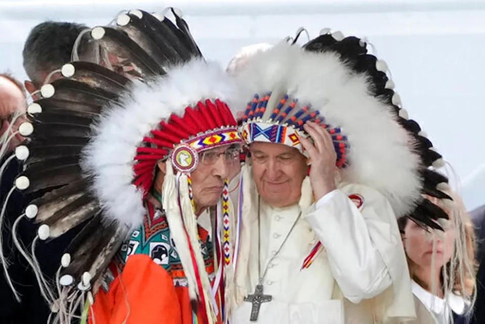 Pope Francis dons a headdress during a meeting with Indigenous communities, including First Nations, Metis and Inuit, at Our Lady of Seven Sorrows Catholic Church in Maskwacis, near Edmonton, Canada, in July 2022 (AP)