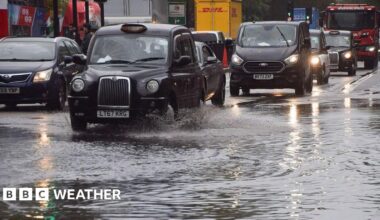 flooded street with cars and taxi's driving through it