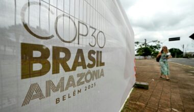 A woman walks past a banner with the COP30 UN Climate Change Conference logo outside the Hangar Convention and Exhibition Center in Belem, Para State, Brazil on November 5, 2025
