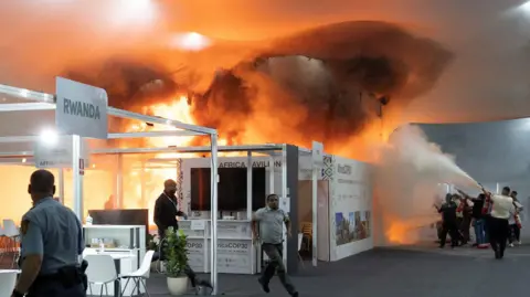 Reuters People use fire extinguishers to put out a fire at the Pavilion of Countries in the Blue Zone 
