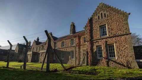 Getty Images A red brick army barracks partly enclosed in a wire fence