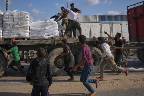 Des Palestiniens s’emparent de sacs de farine, sur un camion transportant de l’aide du Programme alimentaire mondial, à Deir el-Balah, dans le centre de Gaza, le 15 novembre 2025.