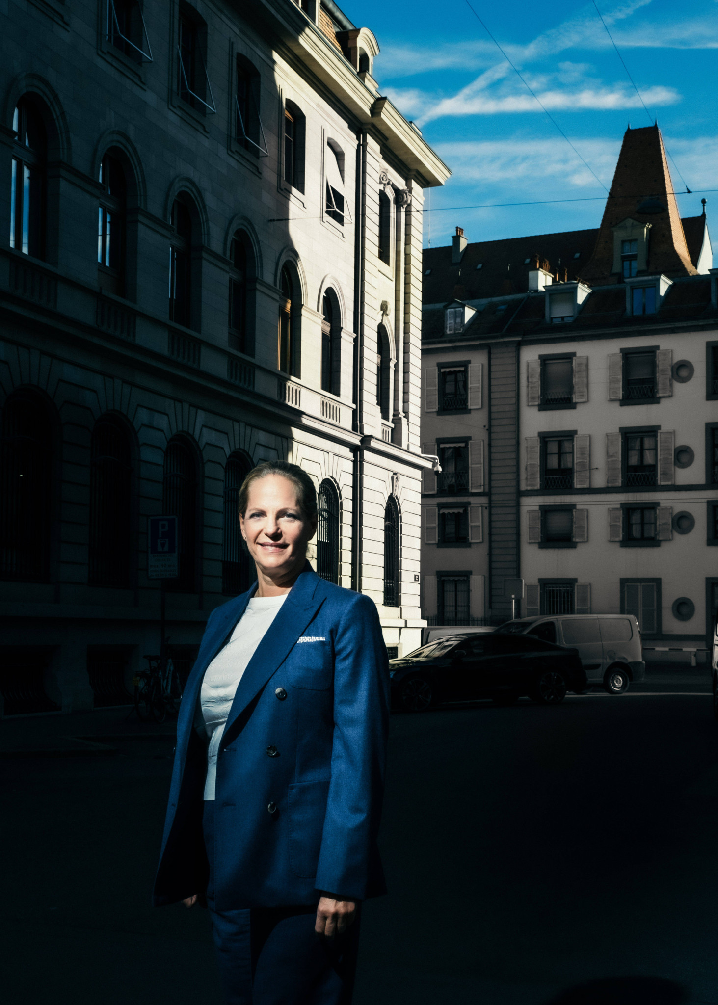 Portrait d’Ariane de Rothschild devant le siège de la banque, habillée en costume bleu, éclairée par la lumière du jour entre les bâtiments. Portrait d’Ariane de Rothschild devant le siège de la banque, habillée en costume bleu, éclairée par la lumière du jour entre les bâtiments.