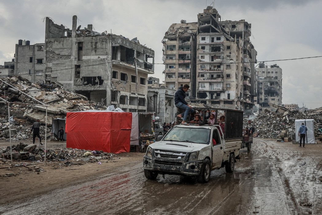 Palestinians drive down a muddy road after the first winter rainfall in a displacement camp in Gaza City on November 14, 2025. Photo: Omar Al-Qattaa/AFP.