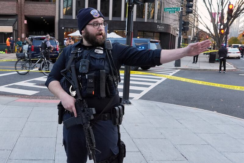 A Washington Metropolitan Police officer directs pedestrians after two National Guard soldiers were shot (Evan Vucci/AP)