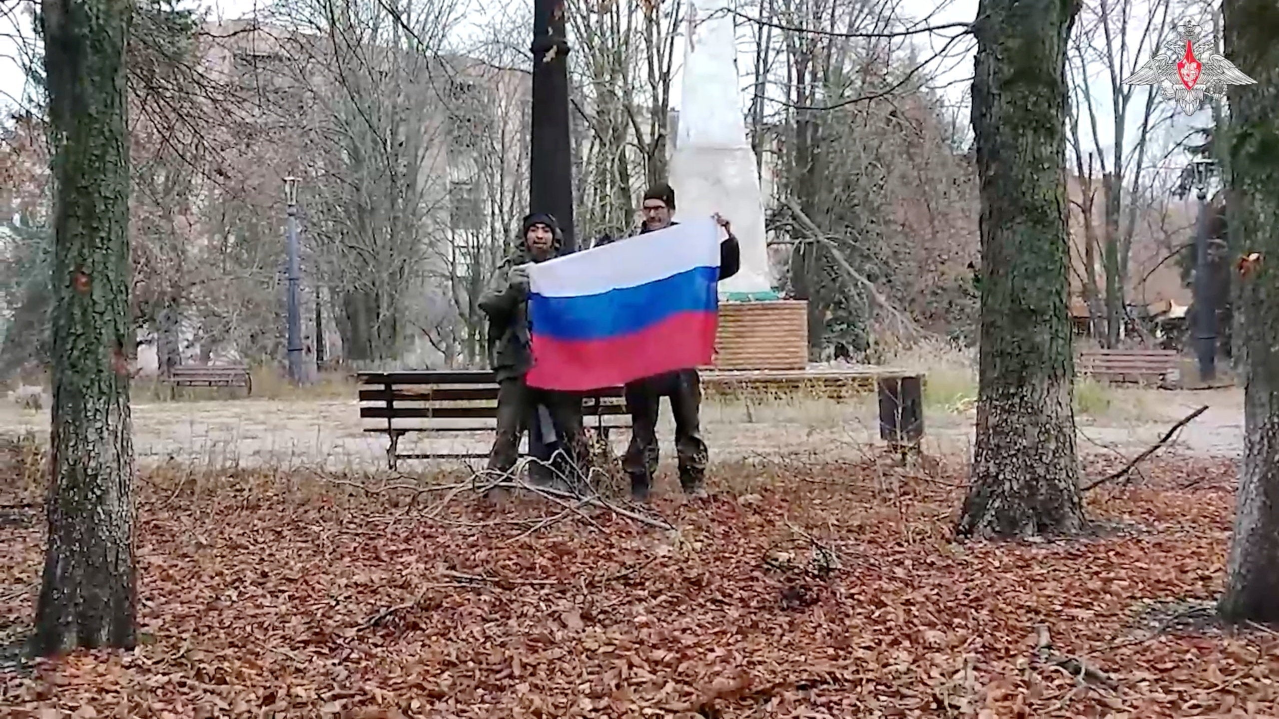 Russian service members hold a Russian flag in a park in Kupiansk, in the Kharkiv Region, Ukraine
