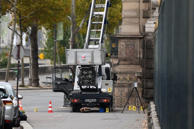 A cherry picker style vehicle is parked outside the Louvre.