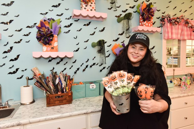 Owner Maggie Calpin holds up Halloween-themed items for sale in...