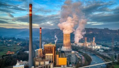 Smoke coming out of the chimneys of a power plant located next to a river.