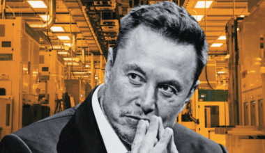 A man in a suit against the backdrop of a factory or industrial setting with orange-tinted lighting.