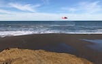 In this photo provided by the Oregon State Police from 2017, a U.S. Coast Guard helicopter searches a beach for two missing men, about two miles north of Cape Blanco, Ore. With the disappearance of the Coast Guard helicopter based in Newport, the local fishing community fears they are at greater risk. 