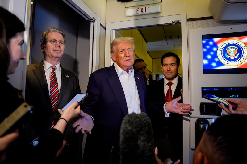 U.S. President Donald Trump, accompanied by U.S. Secretary of State Marco Rubio (R) and U.S. Treasury Secretary Scott Bessent (L), speaks to members of the media aboard Air Force One on October 27, 2025, in flight.