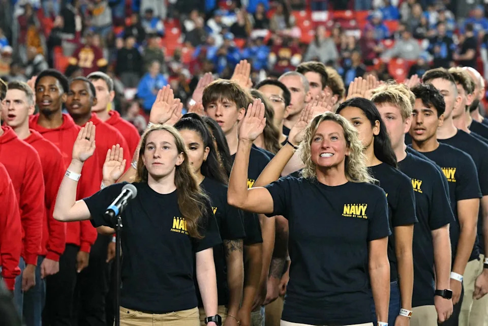 Service members raise their hands as they take the oath during a reenlisting ceremony presided over by Trump during the NFL game between the Washington Commanders and the Detroit Lions at Northwest Stadium in Landover, Maryland (AFP via Getty Images)