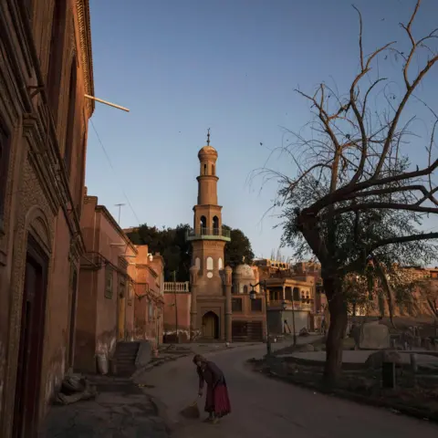 Getty Images A Uyghur woman sweeps outside her house in the old town of Kashgar in this photograph taken in 2017