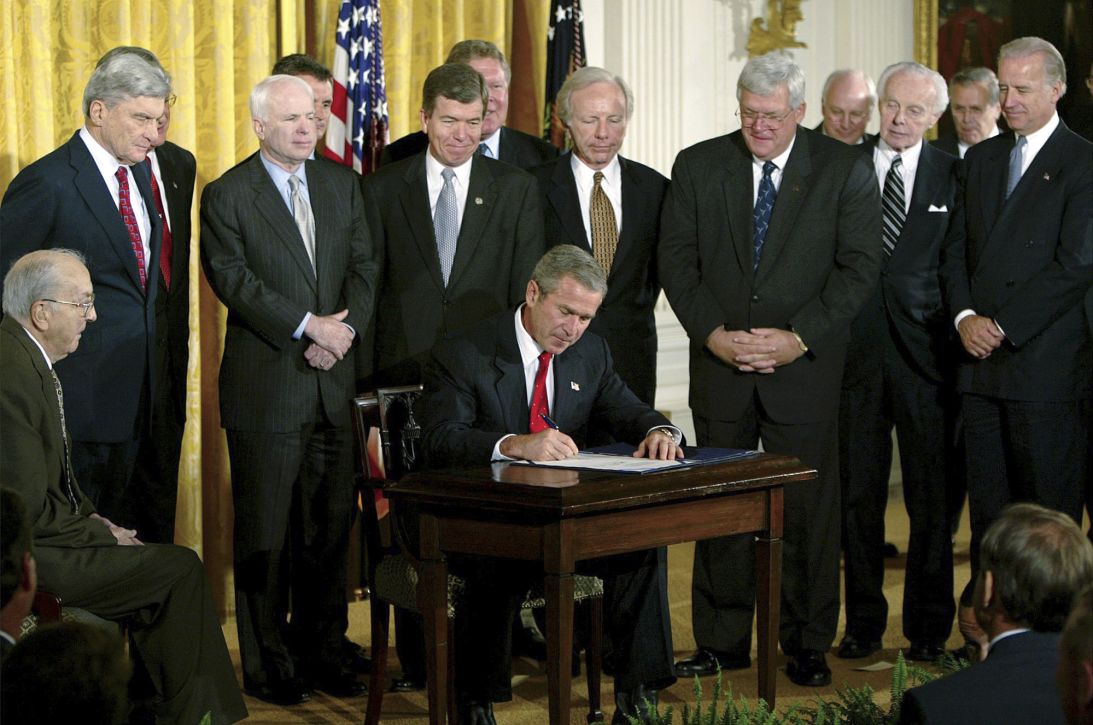 President George W. Bush signs a resolution authorizing the use of force against Iraq, on October 16, 2002, in the East Room of the White House.