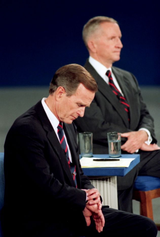 President George H.W. Bush looks at his watch during the 1992 presidential campaign debate with other candidates, independent Ross Perot, top, and Democrat Bill Clinton, not shown, at the University of Richmond, Virgina.