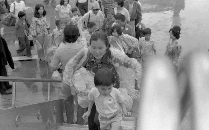 Black and white photo of people walking up steps to an airplane