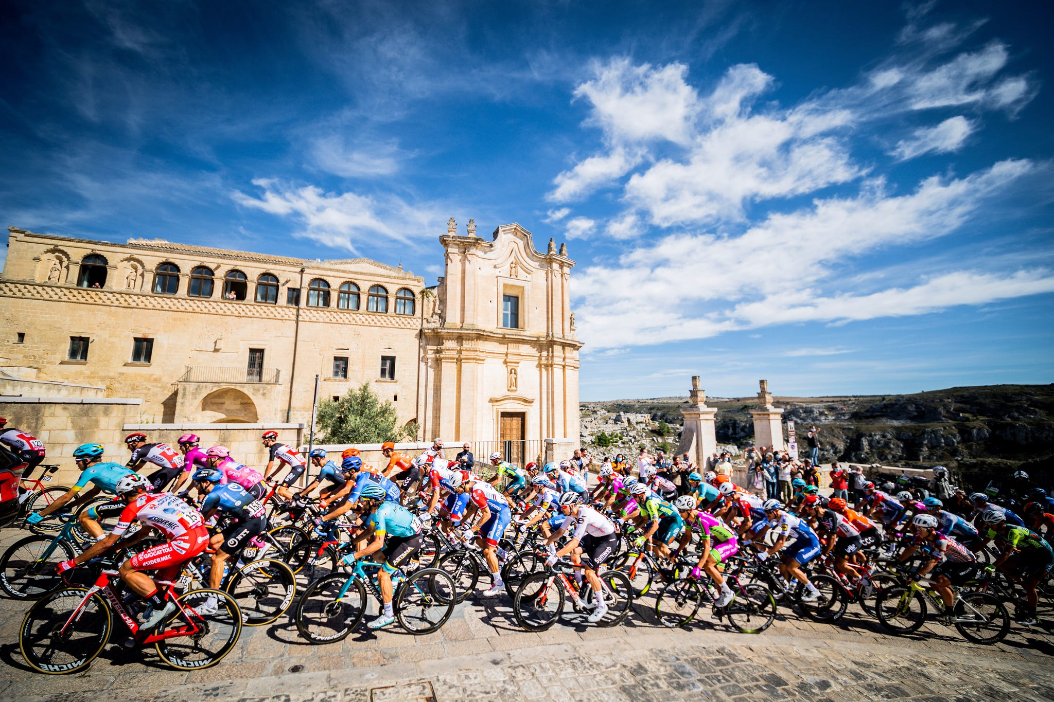 a large group of cyclists racing through an old city