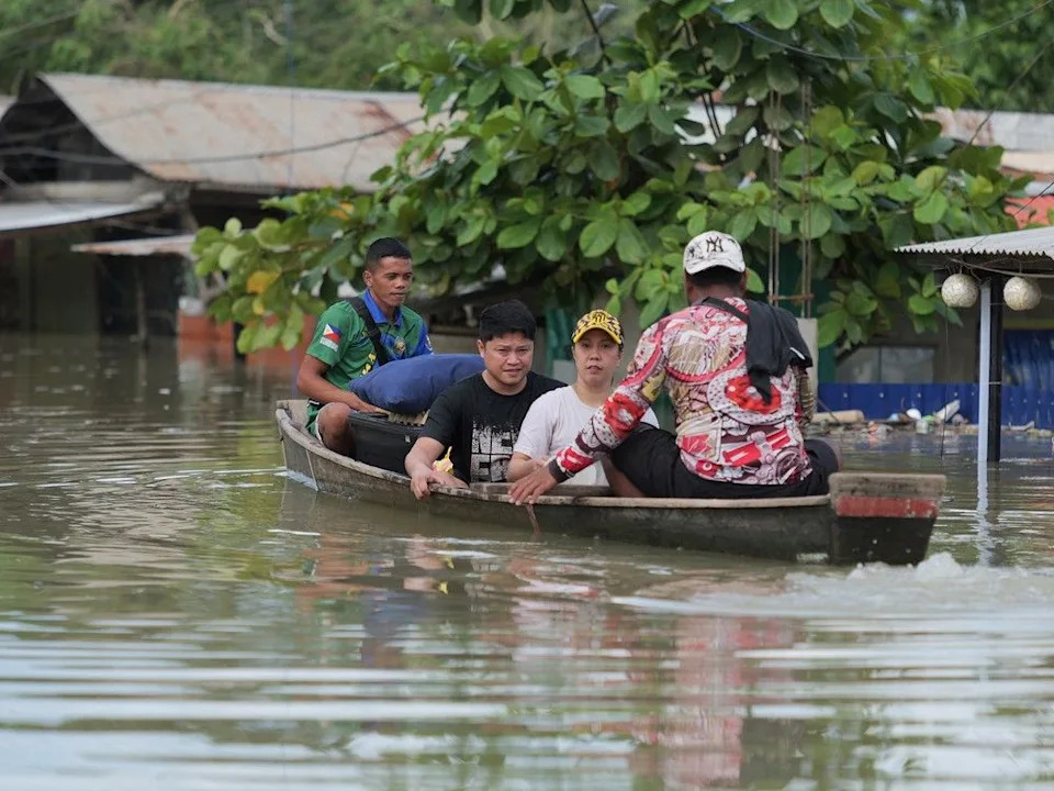 Residents on a wooden boat evacuate from their flooded home at a village in Tuguegarao City, Cagayan province, north of Manila on November 11, 2025, as flood waters continue to inundate homes due to heavy rains brought about by Super Typhoon Fung-wong. Getty photo.