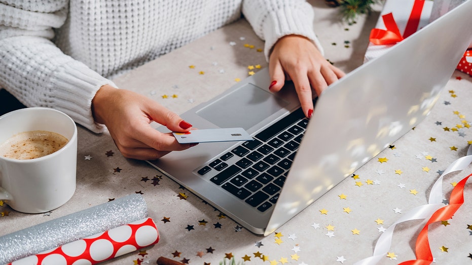 Woman holds a credit card and uses a laptop to shop online