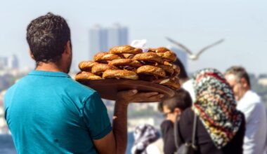 A street vendor carries a tray of traditional sesame-covered bagels known as simit along the Bosphorus waterfront in Istanbul, Türkiye. (Adobe Stock Photo)