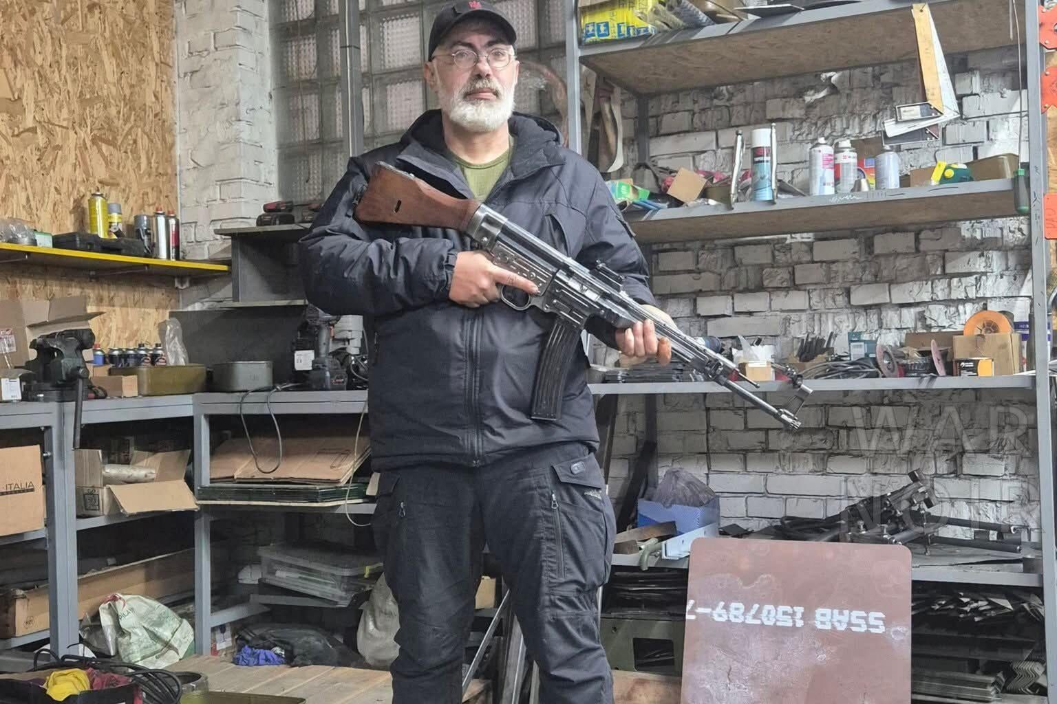 A veteran from the Ukrainian Army, standing in a workshop with a German STG (MP-43 or 44) assault rifle which is chambered in (7.92x33mm) Kurz
