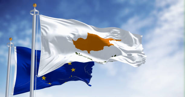 Cyprus and European Union flags waving side by side against a bright blue sky.