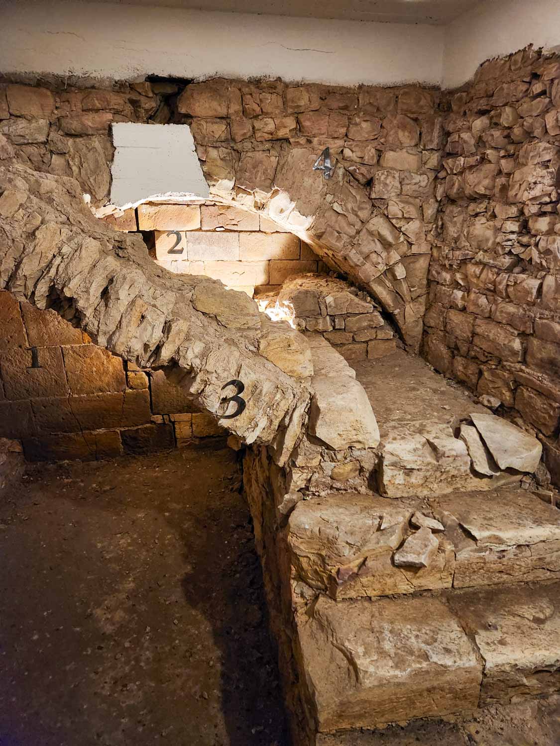 Stone wall, arch and steps supporting the bridge in the Charles Bridge Museum - a visit is one of the things to do in Prague for families