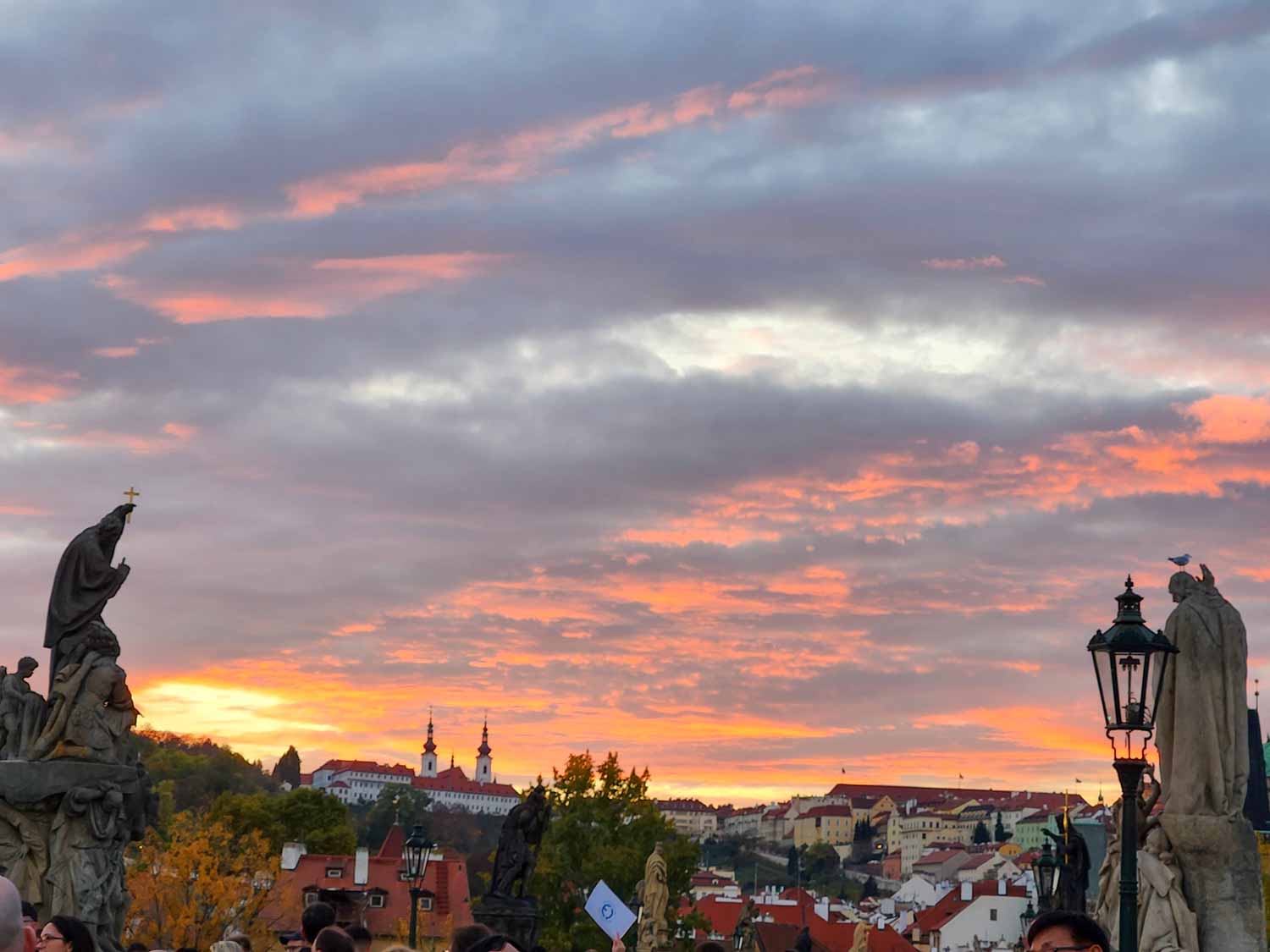 Sunset over teh Charles Bridge with two of the statues visible and castle buildings on the hill beyond - one of the unmissable sights of Prague with kids