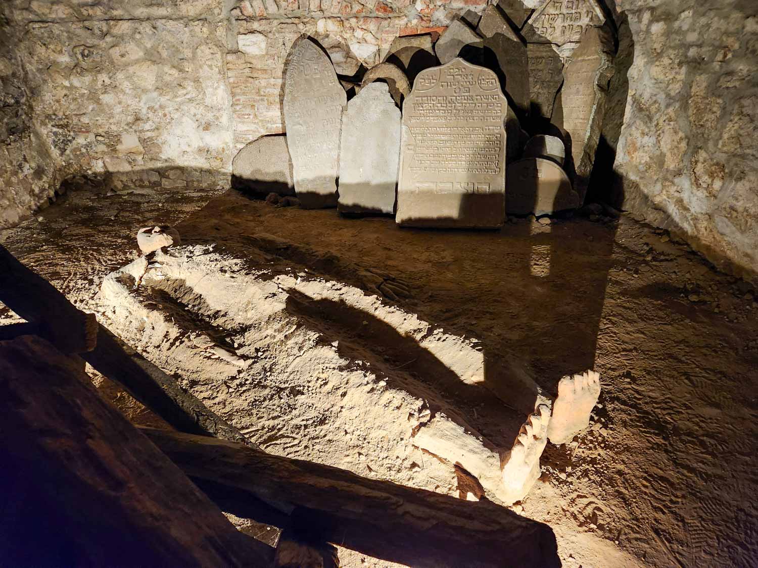 Half-buried figure designed to represent the golem and gravestones in the background at the Museum of Prague Ghosts and Legends - one of the most unusual things to do with kids in Prague