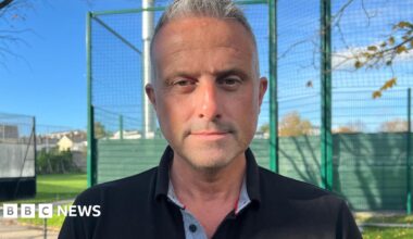 Carl Walker is looking into the camera. He has short grey hair and is wearing a black polo shirt.