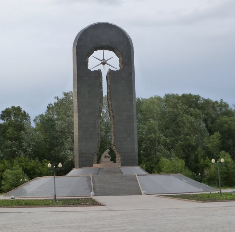 A tall sculpture showing a mushroom cloud shape and a woman's silhouette underneath shielding a child