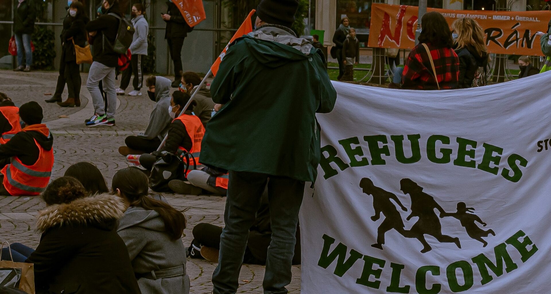 A person holding a banner saying 'Refugees Welcome'.